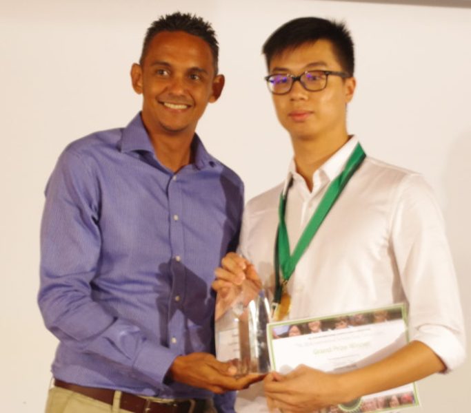 Darren Tan, a student, is being presented his glass trophy.